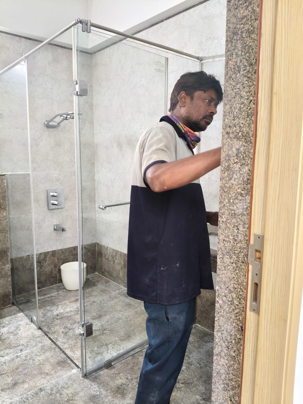 Staff member checking a bathroom glass shower enclosure