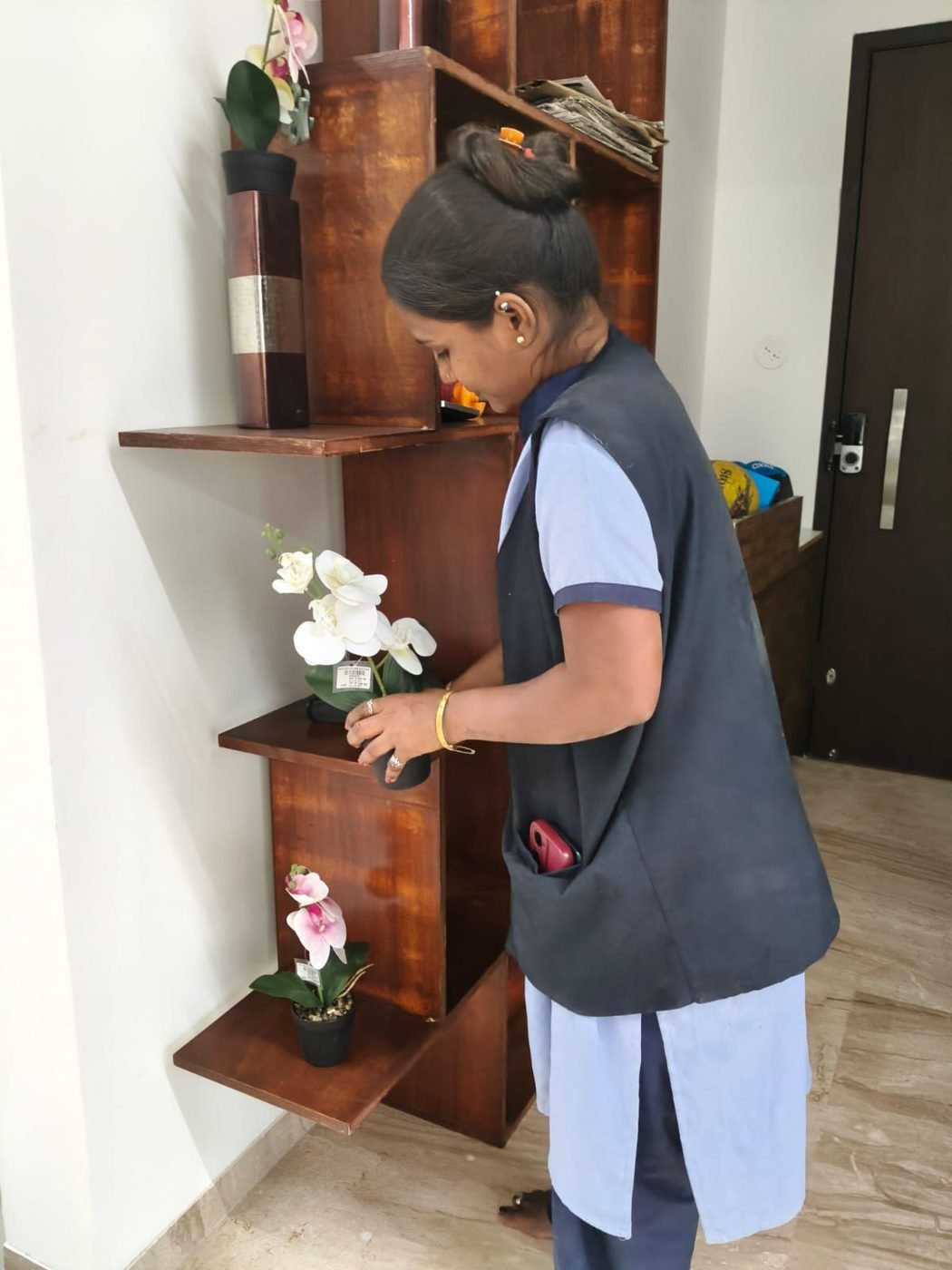Staff member dusting and arranging a shelf